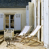 Sunshine on the terrace - wooden loungers in front of a French country house