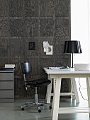 Schwarzweiss - weisser Schreibtisch mit schwarzem Bürostuhl vor dunkler holzvertäfelter Wand