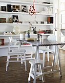 A coffee break on a trestle table with white chairs in front of a shelf