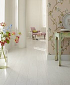 A boudoir with white floor boards and gloriosa flowers in a vase