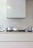 White pots on a gas hob with an extraction hood