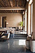 Holzbottiche auf poliertem Betonboden und Blick auf Stufen zum Wohnraum im Mediterraner Haus