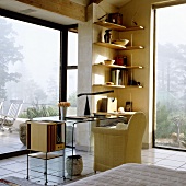 A desk with a panoramic view - an armchair and a glass table with a shelf in the corner of a room with floor-to-ceiling windows