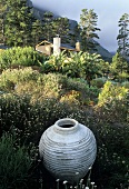 A white amphora in a field with a view of a South African country house set in the wilderness