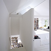 A partitioned attic room with a white stairway and a view into a bedroom