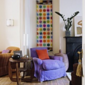 A wooden side table and a purple upholstered armchair next to a fireplace