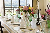 Place settings with wine glasses and vases of flowers