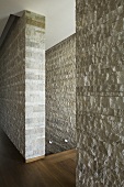 A natural stone wall with a floor-to-ceiling access gap giving a view of the stairwell