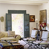 Padded metal chairs in the living room of a country house with an open garden door