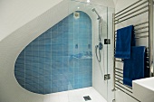 A designer shower cubicle in an attic with blue wall tiles and a stainless steel towel rack