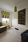 A bedroom with a built-in wardrobe, an open shelf and a ceiling lamp with a green shade