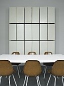 A conference table with brown bucket chairs and a tailor-made wall cupboard with open doors