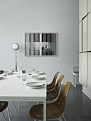 Gedeckter Tisch mit braunen Schalenstühlen im minimalistischen Raum