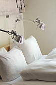 Designer reading lamps with metal shades attached to a bed