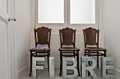 An artistic room installation - metal letters in front of antique chairs