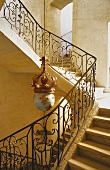 An elegant stairway - stairs with a wrought iron banister and an antique pendent lamp