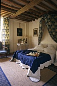 Breakfast in bed - a darkened bedroom with a canopy and a rustic wooden beam ceiling