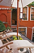 Liegestühle auf Dachterrasse mit Blick auf offene Tür und roter Fassade