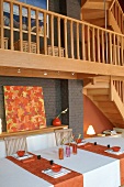 A dining table with Oriental place settings under and wooden gallery with a banister