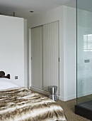 A bedroom - a fur cover on the bed and a built in cupboard with sliding doors