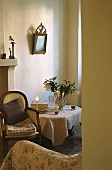 A view of an antique upholstered chair next to a table in the corner of a white room