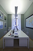Weisser Arbeitstisch mit indirekter Beleuchtung vor grauer Wand