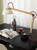 Table lamp with a porcelain shade and adjustable arm on a black surface