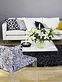 Flower bouquet on a coffee table with patterned chair and white sofa in front of a gray wall