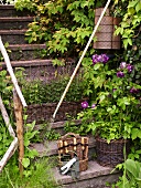 A flight of stone steps with flowers in wicker baskets and garden tools