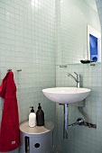 Designer wash basin with mirror in front of glass tile in a bathroom corner