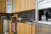 Kitchen cabinets with wood cabinet doors and black wall tiles