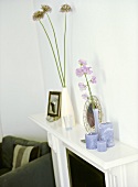 A detail of a modern sitting room showing a painted period fireplace, candles, ceramic vase with flowers