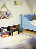 A detail of a child's bedroom with a painted bed, toy storage boxes