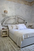 A modern double bed with a rustic headboard and white bedclothes