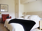 A modern bedroom in neutral colours, double bed, upholstered armchair, fitted wardrobes, upholstered headboard,