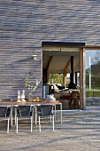 Table and chairs on decked terrace outside modern house