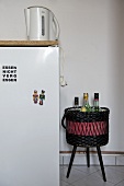 Kettle on worktop and bottles in basket on stool