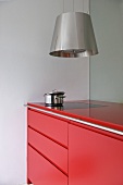 Dunstabzug aus Edelstahl und moderne Küchenzeile mit roter Oberfläche