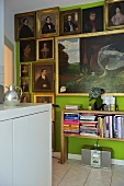 Collection of portrait paintings above book shelf