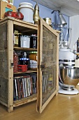 Jars of jam and cds in wooden cabinet on worktop