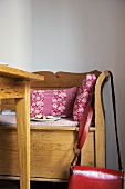 Kissen mit Blumenmuster in rot und weiss auf Sitzbank aus Holz