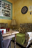 Antiker Holztisch vor altem Sessel und gelber Wand