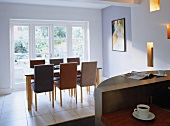 Open plan dining area with table and chairs in front of french doors.