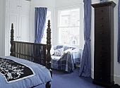 Antique wooden double bed in bedroom with sofa beneath window