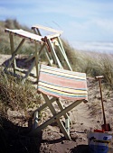 Folding beach stools with striped seats and sand toys with a view of the ocean