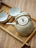Ceramic teapot and beakers on wooden tray