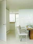 Dining room with wooden table and white chairs.