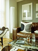 Glass coffee table in front of brown leather sofa