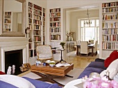 A traditional sitting room with fireplace and built in book shelves, with an open doorway leading to a dining room