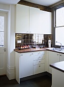 Moderne Küche mit weißen Schränken und dunklen Fliesen an Wand und Boden